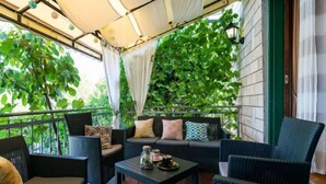 An outdoor seating area with wicker furniture, a table with a decorative jar, and a view of greenery through a white curtain. - Vacation home Otavia by Interhome (Bilice)