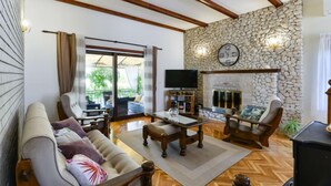 A living room with a stone wall, wooden beams, a fireplace, and a television. - Vacation home Otavia by Interhome (Bilice)
