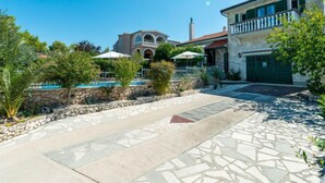 A courtyard with a swimming pool, stone walls, and a two-story building with a balcony. - Vacation home Otavia by Interhome (Bilice)