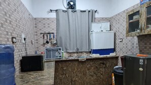 A compact kitchen with a built-in sink, a small refrigerator, and a water dispenser. - Smart 3 bed Apartment With Fast Wi-fi & 24hr Light (Abuja)