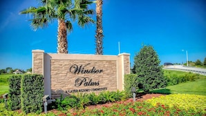 Schild für Windsor Palms, eine Wohnanlage mit Golfplatz, mit angelegtem Garten und Palmen.