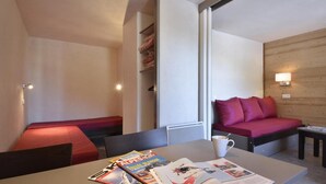 Ein modernes Hotelzimmer mit Bett, einer Sitzecke, einem Tisch mit Zeitschriften und einer Lampe.
