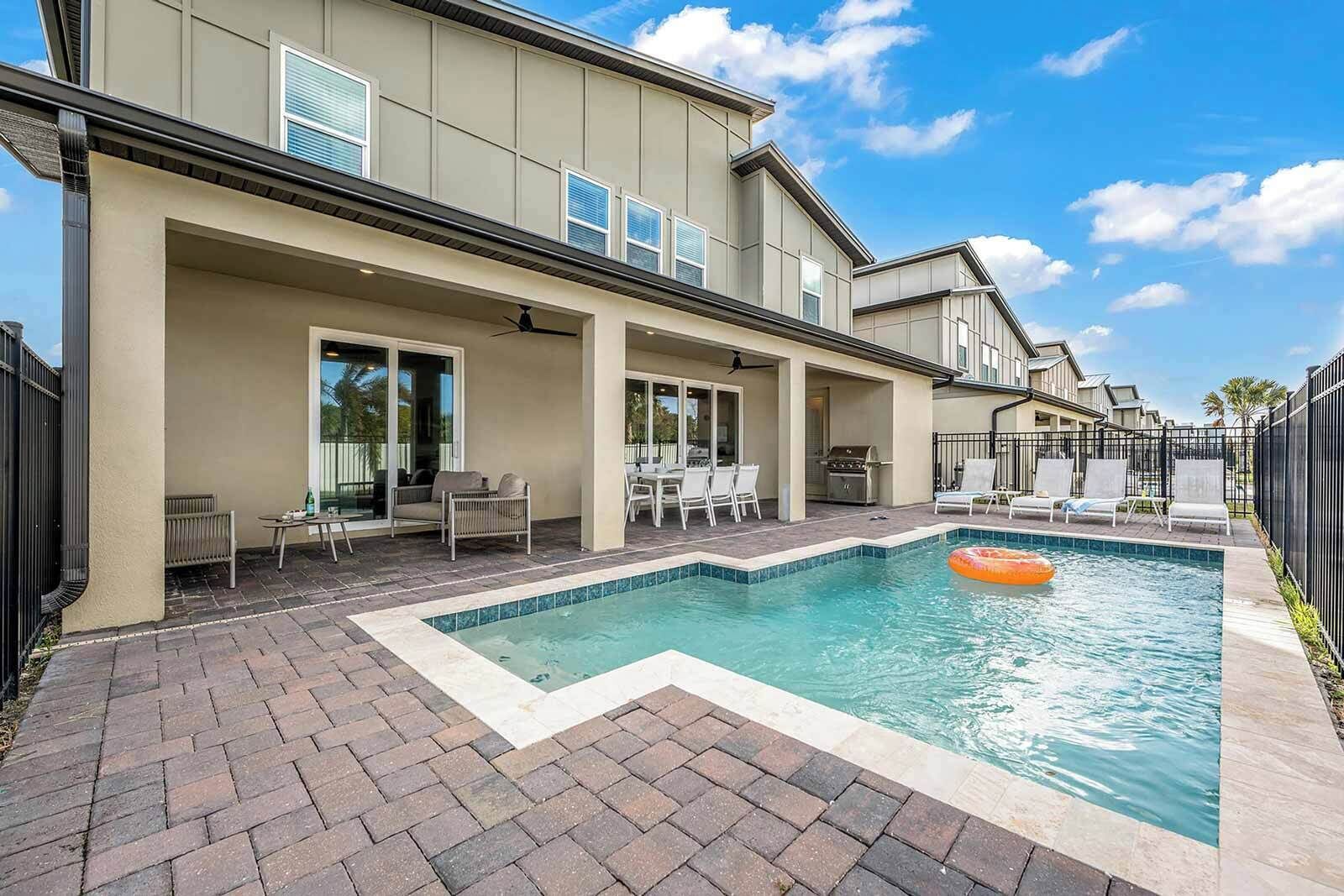 A modern house with a swimming pool, outdoor seating, and a barbecue area.