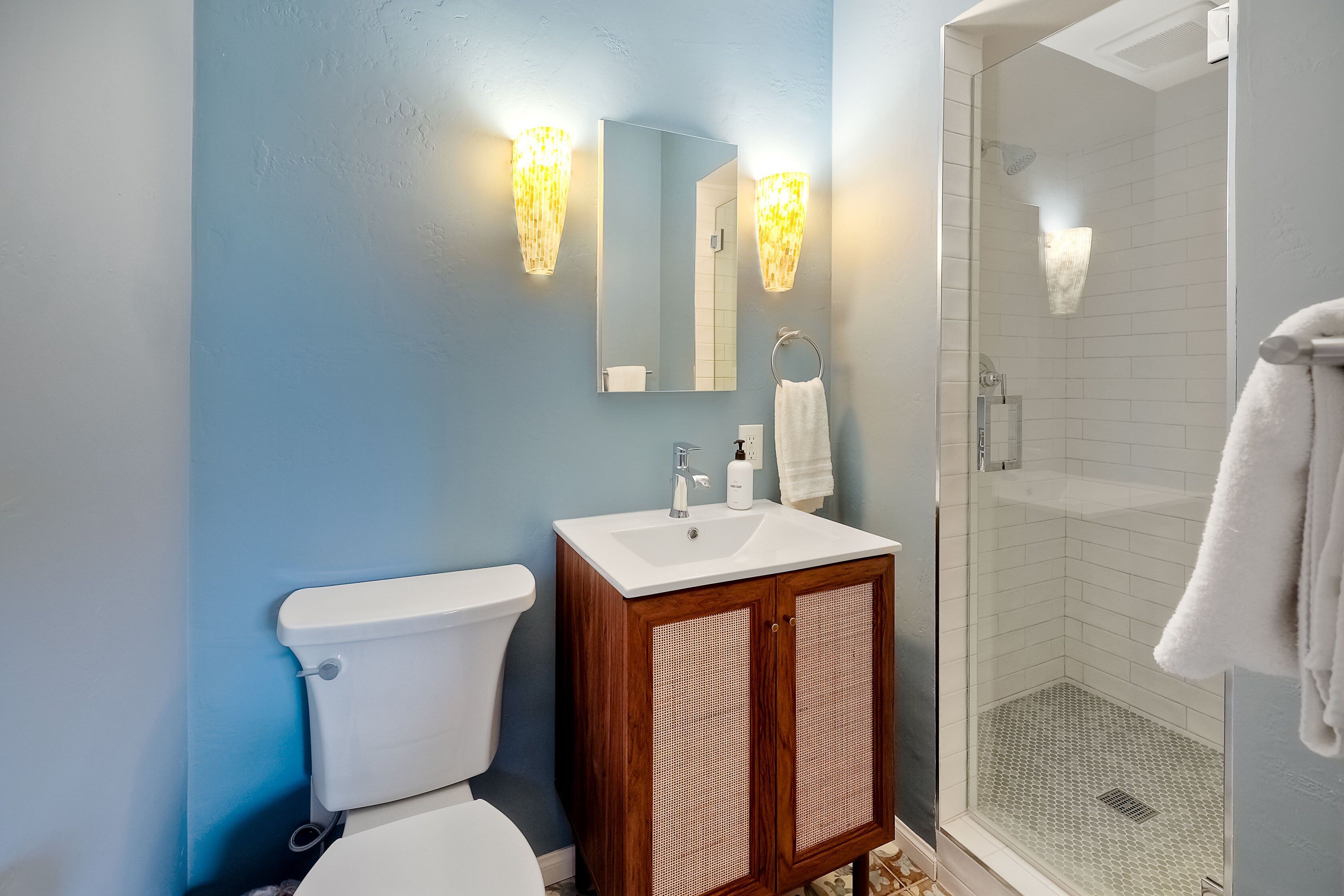 Un baño con inodoro, lavamanos, espejo y ducha.