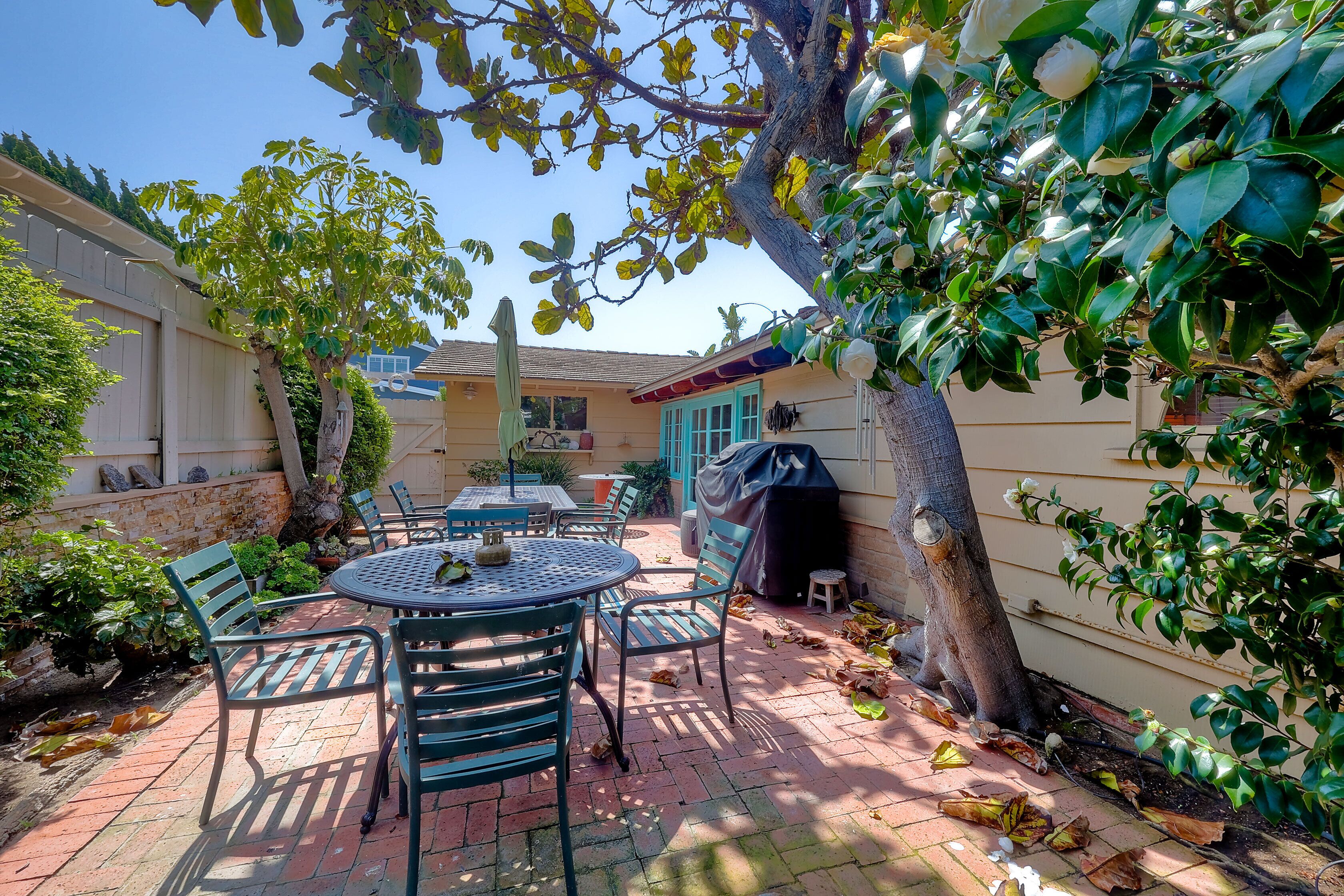 A patio area with a round table and chairs, a barbecue grill, and a covered seating area.
