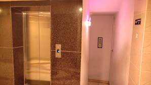 An elevator with a control panel and emergency exit sign. - Sri Maharaja Residency (Tiruchirappalli)