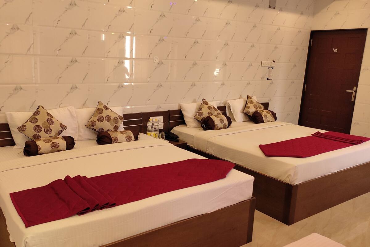 Ein Hotelzimmer mit zwei Betten, jeweils mit roter Decke, weißer Bettwäsche und gemusterten Kissen.