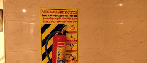 A fire extinguisher mounted on a wall with a safety instruction sign beside it.