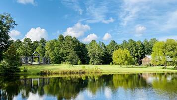 Une propriété paisible au bord d’un lac, comprenant un chalet en bois et une grange, le tout entouré d’une végétation luxuriante et d’arbres.