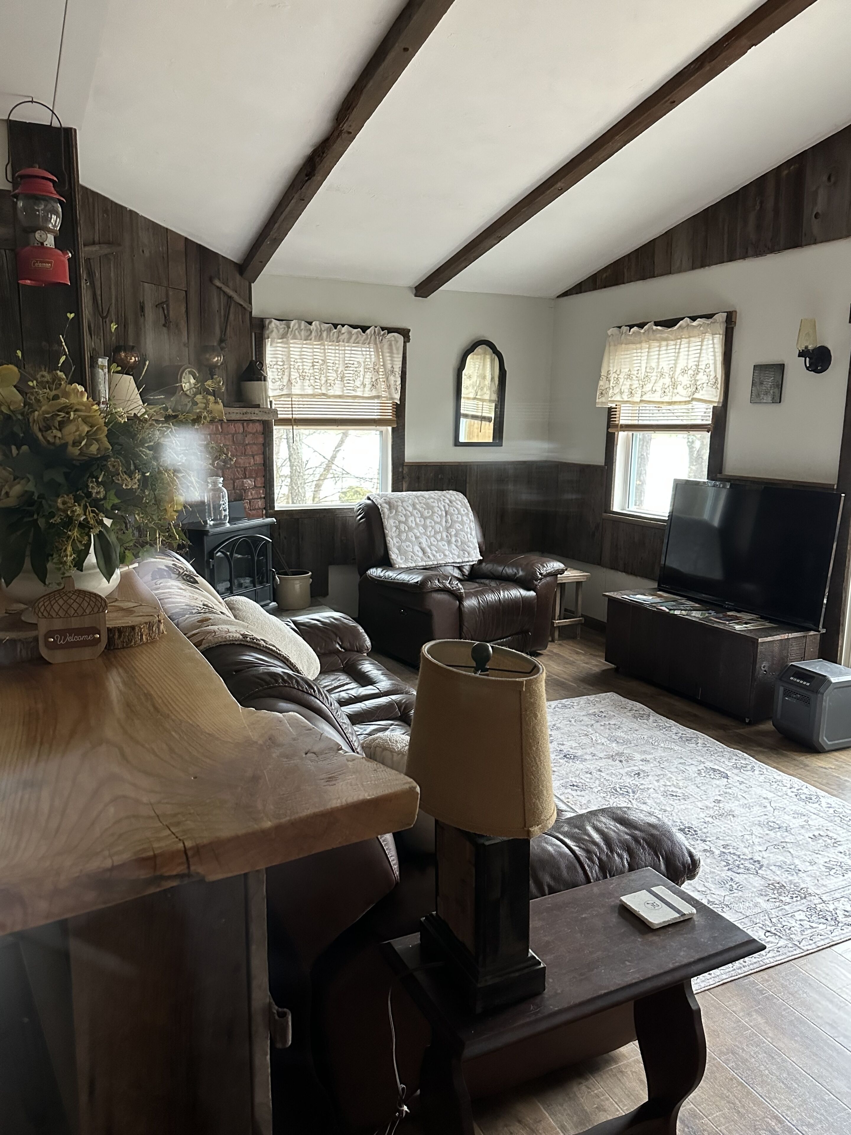 A cozy living room with a fireplace, leather sofas, a coffee table, and a TV.