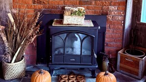 A rustic room with a brick fireplace, a wooden clock, and decorative pumpkins. - Cozy Roscoe Lakefront Cabin (Roscoe)