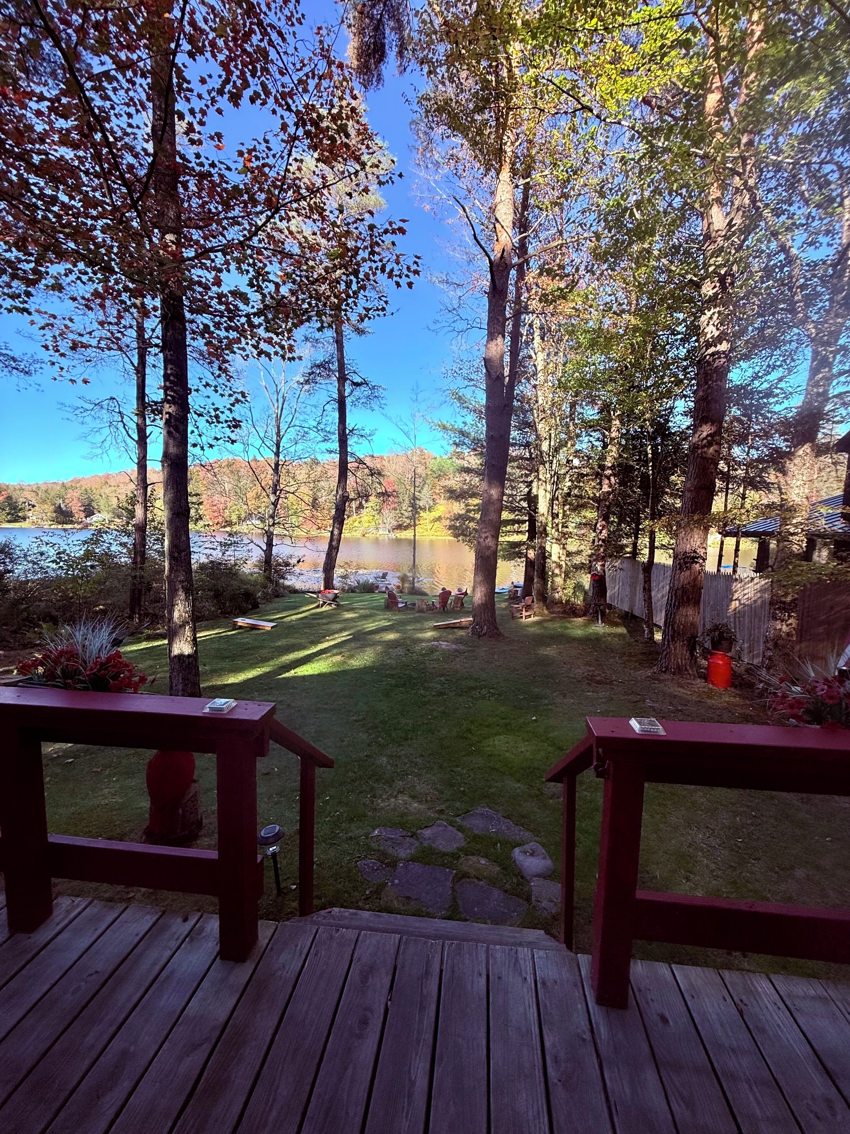 Une terrasse offrant une vue sur un jardin comprenant une pelouse, des arbres et un lac situé au loin.
