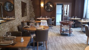Een restaurant met stenen muren, meerdere klokken en verschillende soorten zitplaatsen.