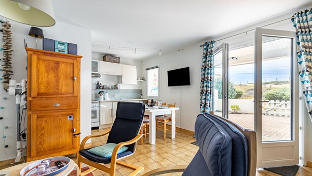A compact living space with a kitchenette, a dining area, and a view through a glass door.