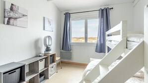 A bedroom with a bunk bed, a desk with a mirror, and a window with curtains.