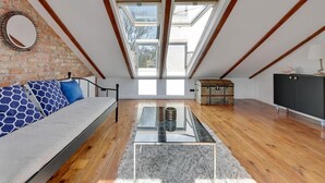 A loft bedroom with a sloped ceiling, skylights, a sofa, a glass coffee table, and a chest of drawers. - Sopot Cosy ATTIC (Sopot)
