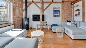 A cozy living room with a fireplace, a sofa, a TV, and a view of the city. - Sopot Cosy ATTIC (Sopot)