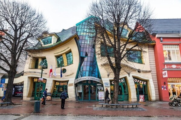 Un edificio con varias cafeterías en la planta baja, que destaca por su diseño arquitectónico único con una fachada curva y grandes ventanales.