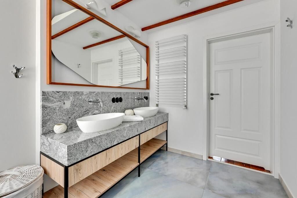 Un baño moderno con lavamanos doble, tocador de madera y un espejo grande.