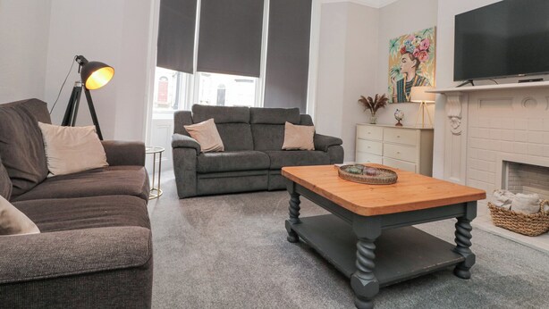 Una sala de estar con un sofá, una mesa de centro, una lámpara, una chimenea y un televisor.