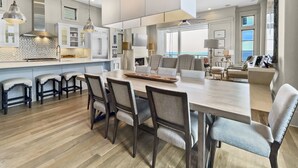 A modern kitchen with a large island, bar stools, and a dining area with chairs.