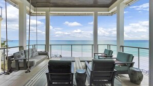 A covered outdoor seating area with a view of the beach.