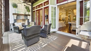 Une terrasse couverte, aménagée avec des meubles en osier, un barbecue et une cheminée.