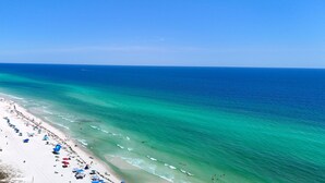 A beach with clear turquoise waters and a sandy shore lined with umbrellas. - Summer Wind 7 Bedroom Home by RedAwning (Santa Rosa Beach)