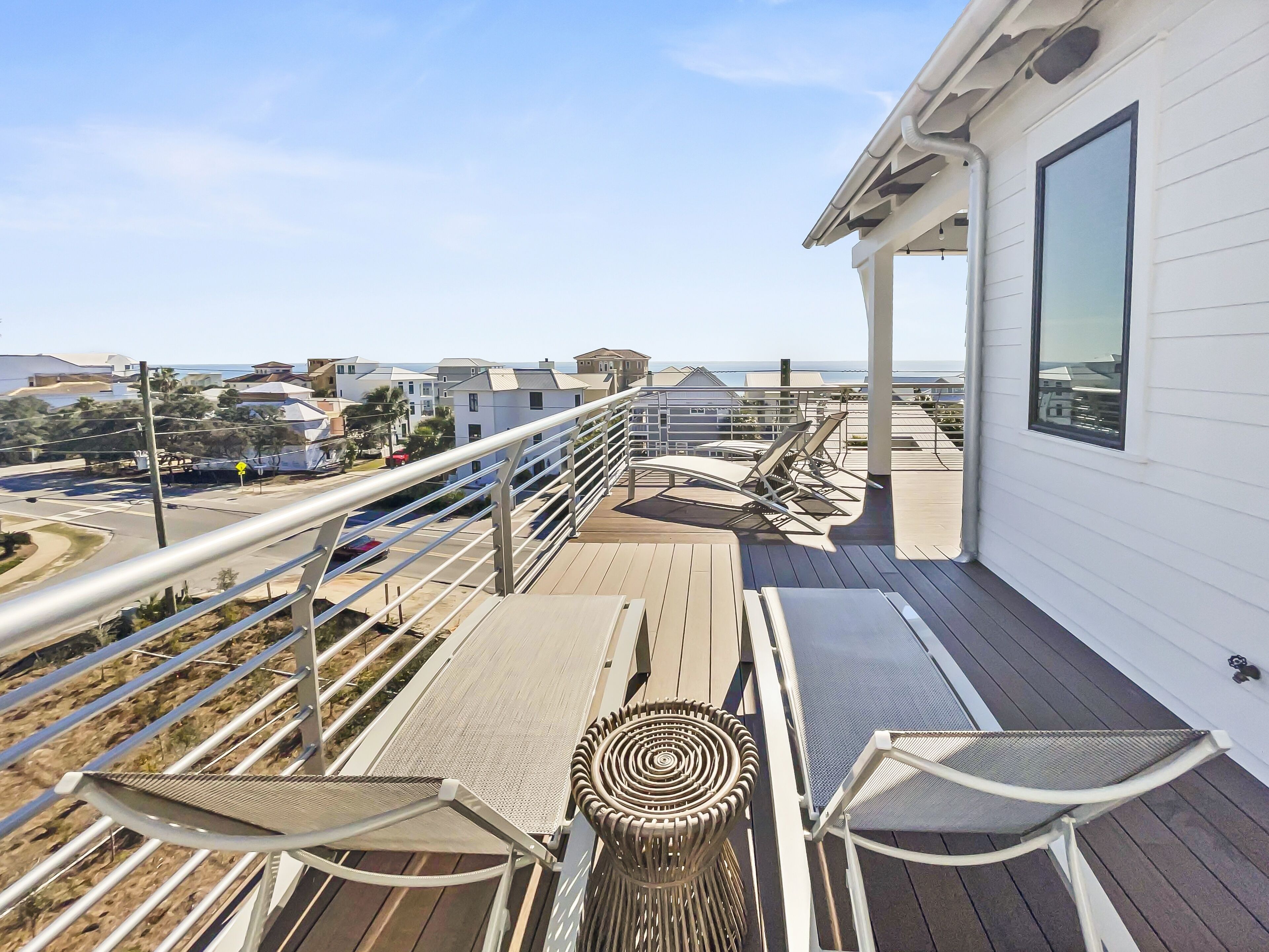 A balcony with a view of the ocean, a railing, and a table with chairs.