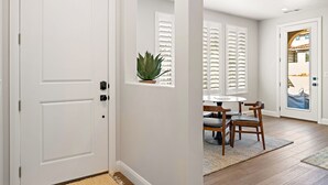 A white door with a potted plant and a window with shutters.