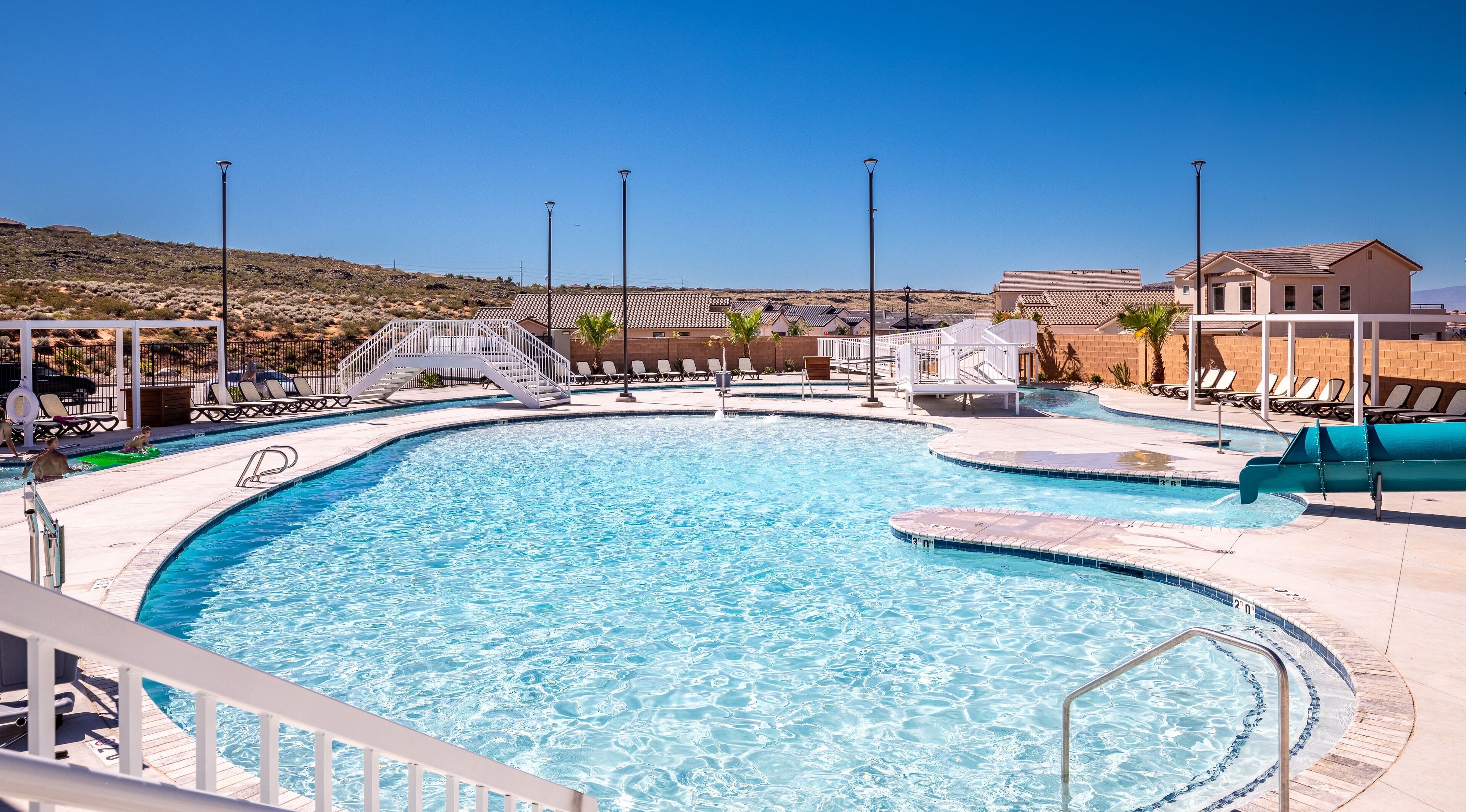A large outdoor swimming pool with multiple lanes, surrounded by sun loungers and a covered seating area.