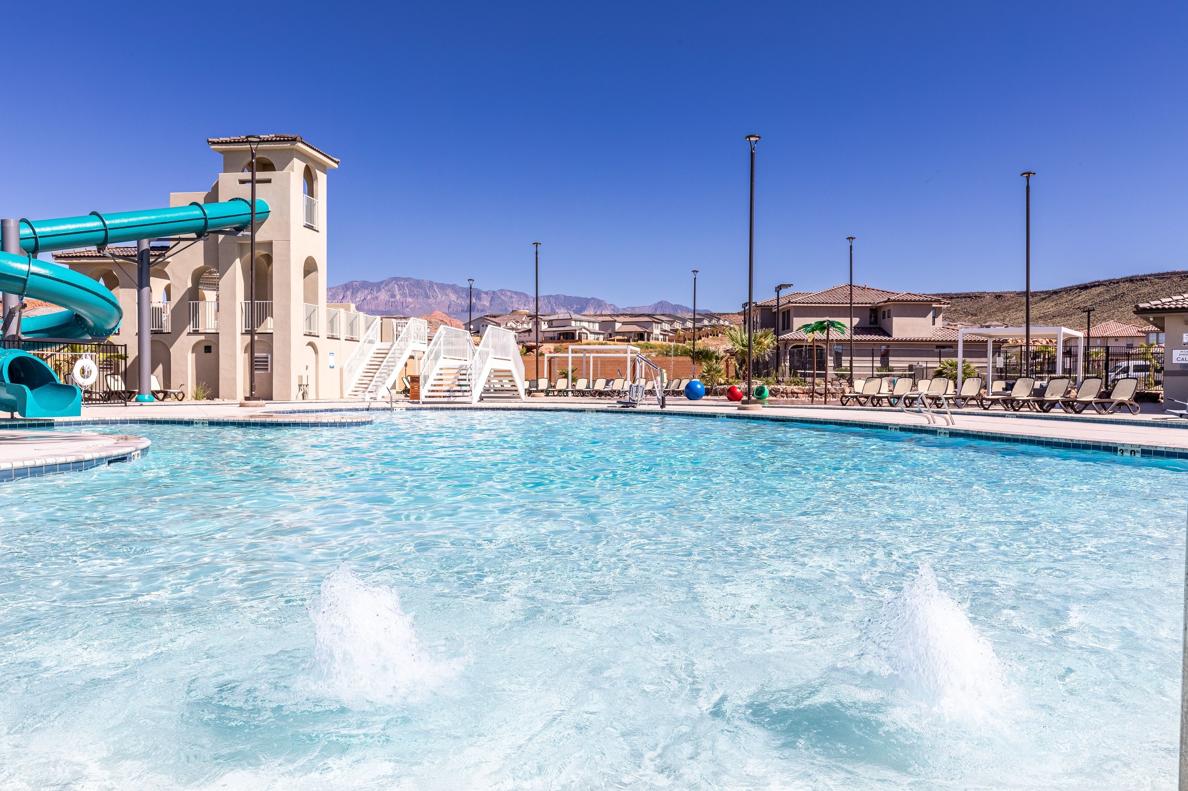 A swimming pool with a water slide and a view of a mountain range.