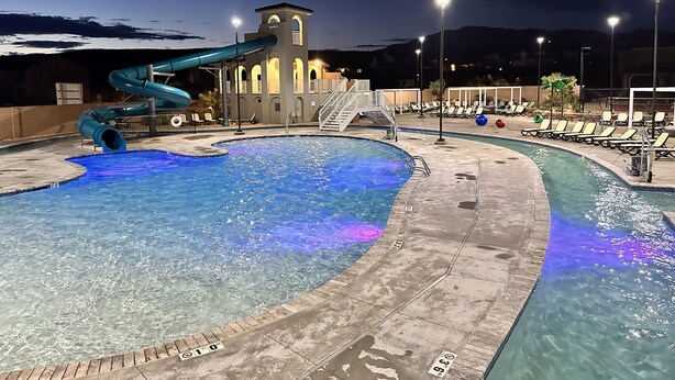A swimming pool with a water slide and a tower structure in the background.