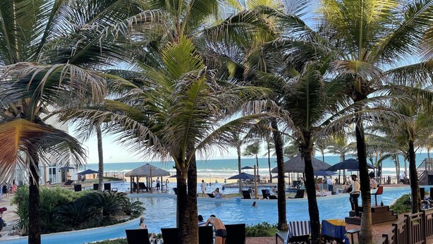 A pool area with lounge chairs, a small pool, and a view of the beach. - Apartment inside a beachfront hotel (Aquiraz)