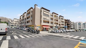Un edificio de varios pisos con una planta baja comercial, un estacionamiento y cielo despejado.
