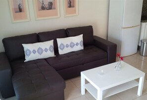 A dark brown sofa with two white pillows, a white coffee table, and a small vase with flowers.