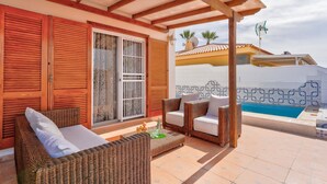 A covered outdoor seating area with wicker furniture, a pool, and a building with a tiled exterior. - Vacation Villa 'Ocean View 3bedroom  with Pool' with Sea View, Wi-Fi and Air Conditioning (Callao Salvaje)