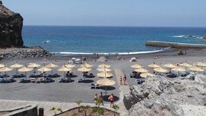 A beach with umbrellas, lounge chairs, and rocky cliffs. - Vacation Villa 'Ocean View 3bedroom  with Pool' with Sea View, Wi-Fi and Air Conditioning (Callao Salvaje)