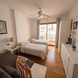 Une chambre avec deux lits, un bureau, une chaise, une télévision et une fenêtre avec des rideaux.
