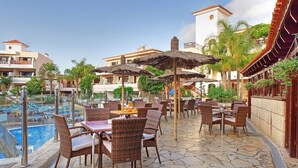 Et resortområde med pool, liggestole, parasoller og en fliseterrasse.