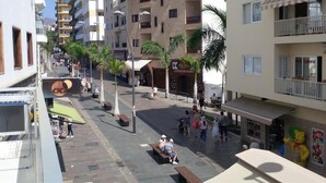 Une rue bordée d’immeubles à plusieurs étages, de palmiers et où l’on voit des gens se promener.