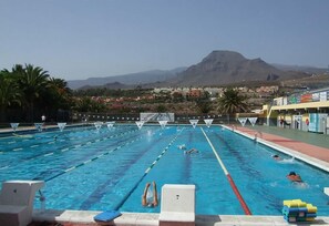 Uma piscina com pistas demarcadas, uma torre de salva-vidas e uma montanha ao fundo.