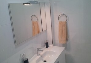 A bathroom with a white sink, a mirror, and two towels hanging on towel rings.