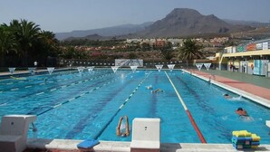 A swimming pool with lanes, a lifeguard tower, and a mountain in the background.