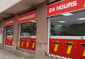 A supermarket with a 24-hour sign and multiple '7 DAYS' signs. - Pleasant Stay in the Heart of Plaza Los Cristianos – Vacation Apartment (Los Cristianos)