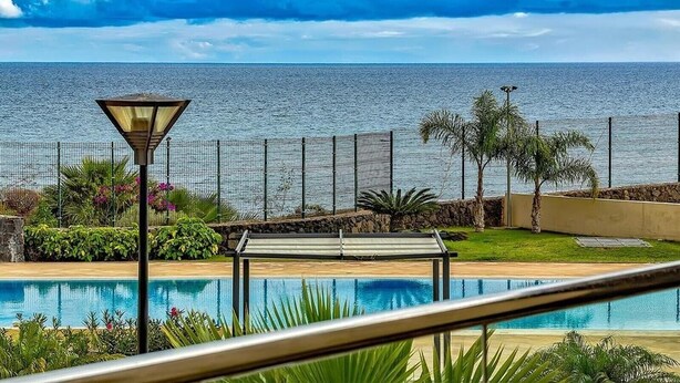 Piscina com vista para o mar, um poste de luz e uma cerca.