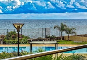 A pool with a view of the sea, a lamp post, and a fence.