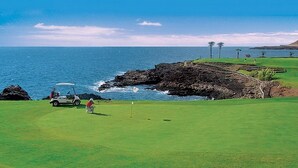 Um campo de golfe com vista para o oceano e a costa rochosa.