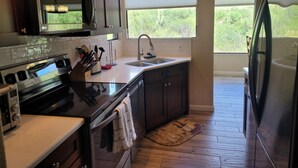 Una cucina moderna con elettrodomestici in acciaio inossidabile, un'ampia finestra e un pavimento in legno.