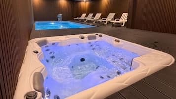 A hot tub with jets, surrounded by lounge chairs and a pool.